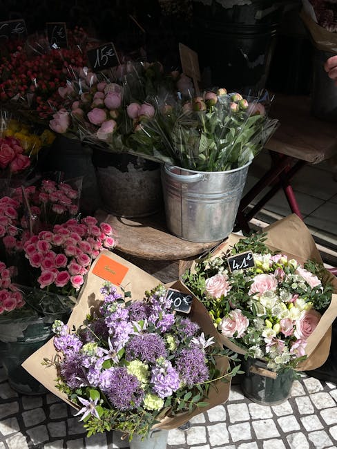 A display of fresh floral arrangements at Enfield Flowers, arranged on a rustic wooden surface in a flower shop setting. The bouquet in the foreground features purple and lavender blooms, including as