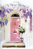 The photograph shows a sunlit Enfield entrance that seems to hold its breath in a moment of gentle anticipation. A pastel pink front door takes centre stage, its colour warm yet understated, surrounded by whitewashed walls that give the scene a soft, Mediterranean brightness even on a typical North London day. From above, wisteria cascades in flowing strands of lavender and pale purple, each blossom hanging like a tiny bell, together forming an arch that drapes down the sides of the doorway. The clusters of flowers overlap and intermingle, creating a textured curtain that would sway lightly with every breeze coming up from nearby Enfield Chase or across the gardens off Baker Street. Sitting proudly on the doorstep is a stylish grey bucket, its surface matt and slightly weathered, holding a lush, hand-crafted arrangement of white and cream roses. The roses are full and rounded, their petals layered in spirals that catch gentle, diffuse light, lending them a creamy luminosity. Fresh green foliage peeks between the blooms, adding natural depth and movement. A soft pink ribbon is tied around the bucket in a simple bow, its tone echoing the painted door and tying the whole composition together. The mood is that of a housewarming tableau: hopeful, calm, and quietly celebratory, as if the flowers are there to greet the new homeowners the moment they step onto the path. It feels like the work of a local Enfield florist who understands how a few carefully chosen blooms can make any new house feel instantly warm, loved, and ready for the stories to come.